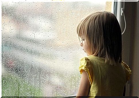 little girl looking through a rainy window