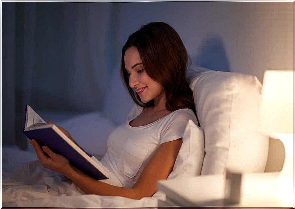 Picture of a happy woman reading in bed.